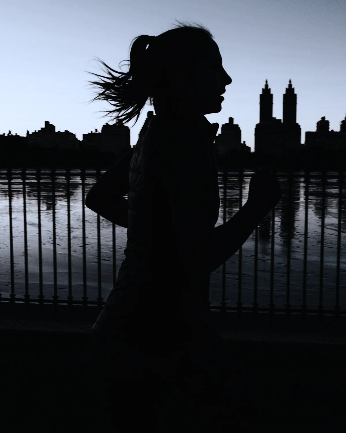 A runner at dusk, silhouetted against a city skyline